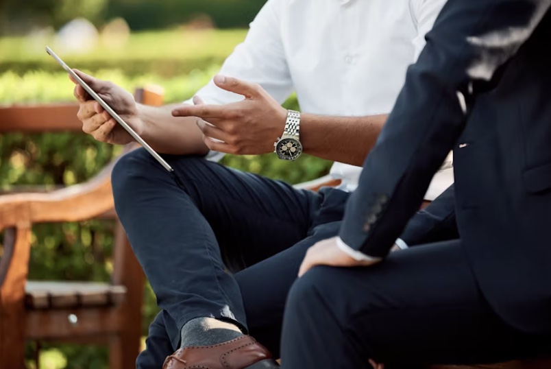 a person on a tablet talking to someone while sitting on a park bench