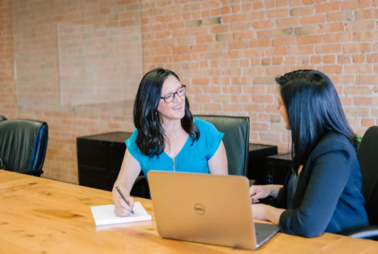 two people sitting at a computer talking