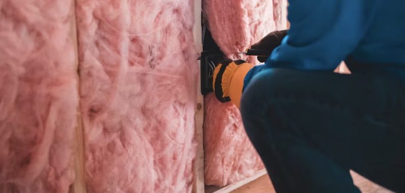 a person putting insulation in a wall
