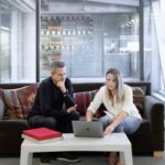 two people on a couch looking at a computer and negotiating