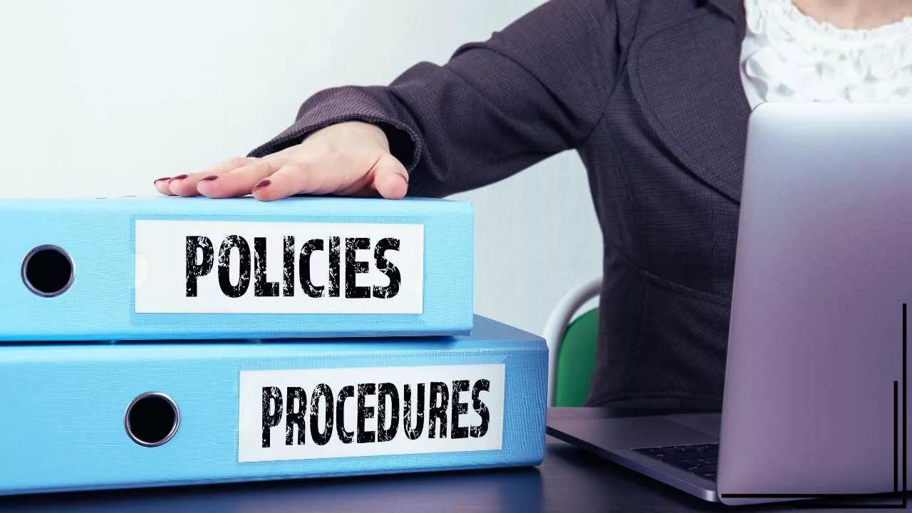 a person with their hand on a few binders that says policies and procedures